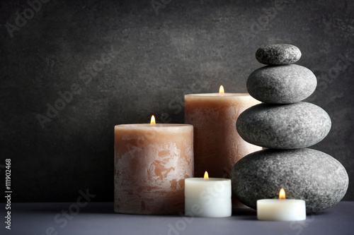 Composition of spa pebbles and candles on grey background
