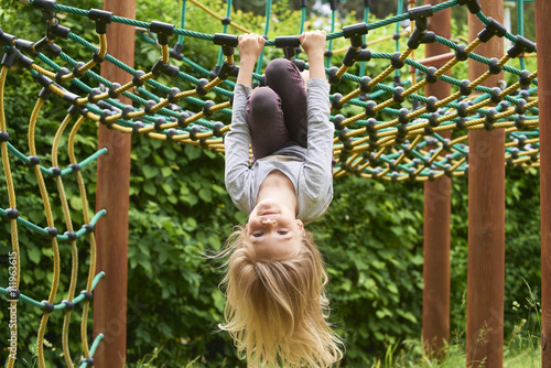 Portrait of Happy little blond girl playing on a rope web playground outdoor