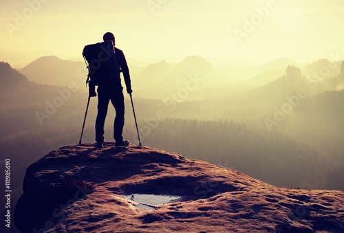 Hiker with broken leg in immobilizer. Deep misty valley bellow silhouette