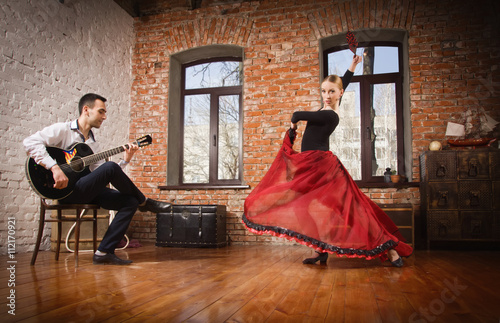 Young woman dancing flamenco and a man playing the guitar