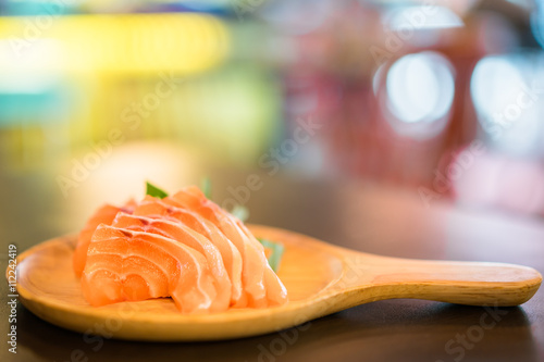 Sliced salmon sashimi served on wooden platter, Japanese food delicious menu, bokeh blurred background with copy space