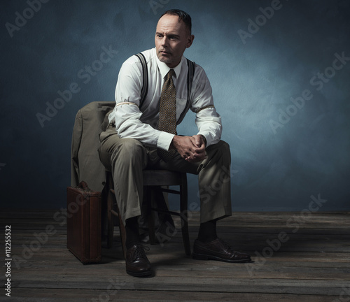 Retro 1940 businessman sitting on chair in room.