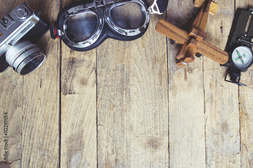 Vintage retro travel background. Retro camera, glasses, balsa wood model airplane and compass on wooden table background. .