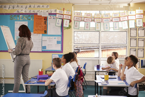 Primary school teacher writing on a flip chart in a lesson