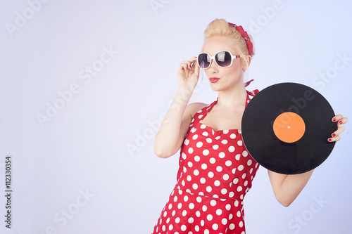 Pin-up girl in vintage dress holding a vinyl record 