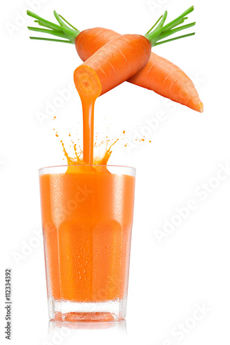 Pure carrot juice pouring out from fruit in glass