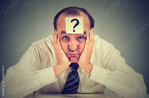 clueless business man with question mark sitting at table