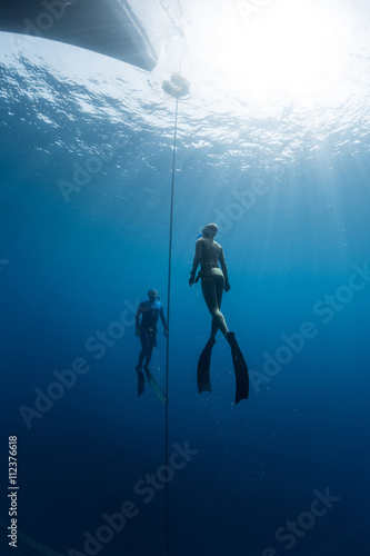 Two free divers swim under the water