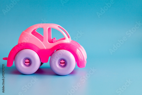 Colorful plastic toy car on a blue background for children.