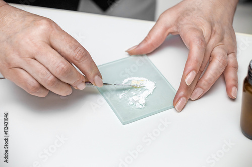 Woman's hands with dental tool mixing white cement