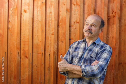 Elderly man looking away dreamily on a wooden background