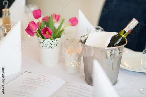 Wino w pojemniku z lodem i różowe kwiaty tulipany zdobiące stół w restauracji