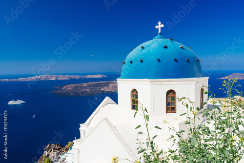 Beautiful blue dome church and view of voclanic caldera in Imerovigli, village on Santorini island, Greece