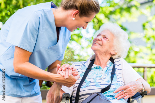 Altenpflegerin gibt Seniorin Glas Wasser zu trinken