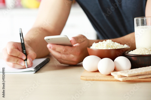 Man counting calories on table