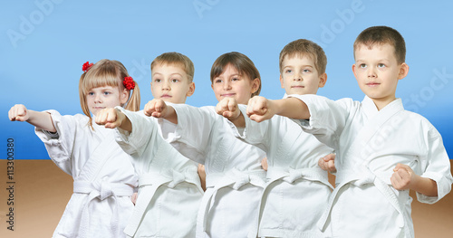 Kids in karategi are hitting punch arm
