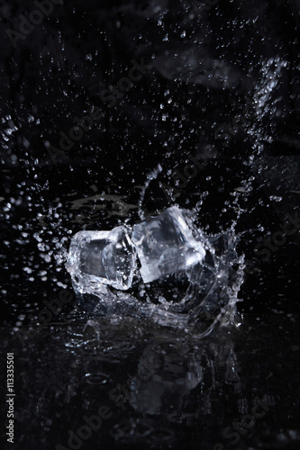 Two ice cube flying with splashes on a black background