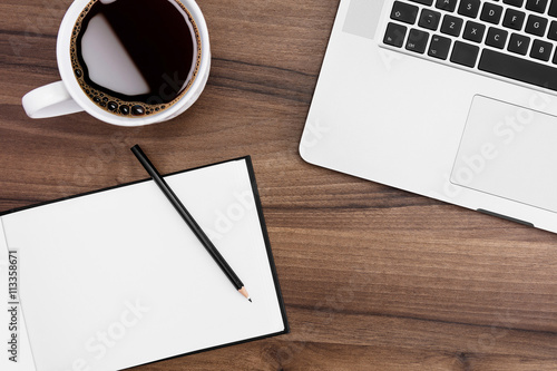 Desk with open notebook, MacBook, and coffe