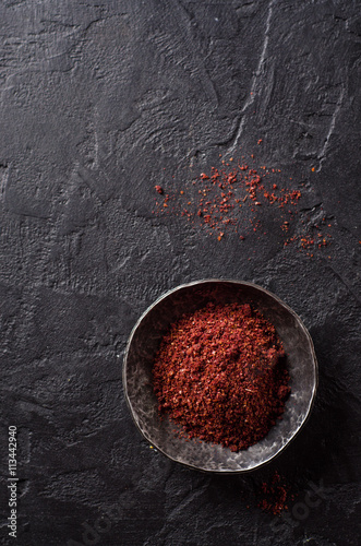 sumah or sumak - east spice in metal bowl on dark background. Selective focus. Top view.Background with place for some text