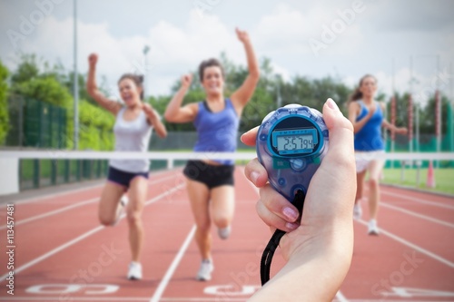 Composite image of a woman holding a chronometer to measure performance of sportswomen