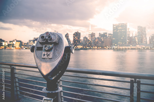 Pay binoculars in Long Island City with the Manhattan skyline at sunset in the background. travel, vacation, sightseeing, new york, tourism, and urban living concept