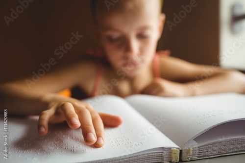 Little girl using his right hand to read braille