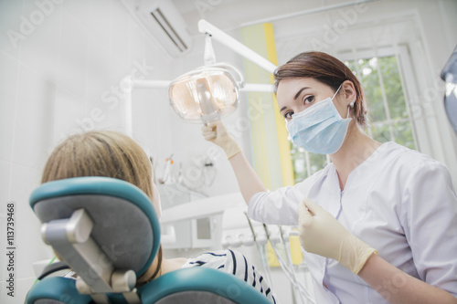 young woman doctor in a dental clinic. the dentist sits in the Cabinet beside the chair with the patient