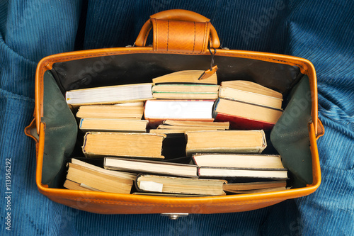 Stack of hardback books in an old suitcase with.