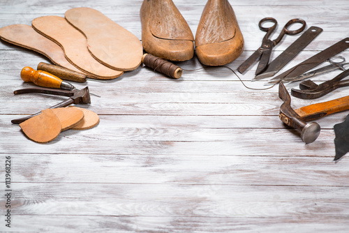 Set of tools for shoemaker on white wooden background. Copy space.