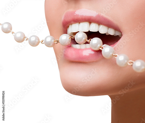  Woman smiles showing white teeth, holding a pearly necklace into the mouth, toothcare concept