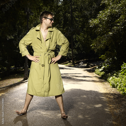 Pervert exhibitionist in coat in summer city park