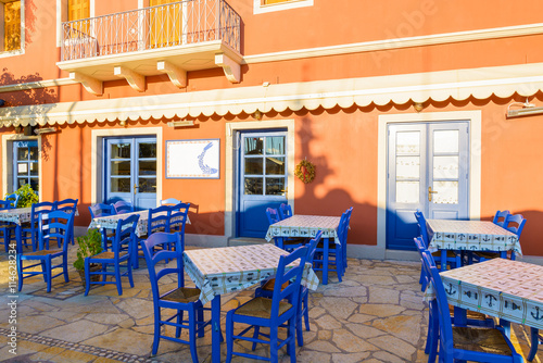 Blue chairs with tables in front of traditional Greek tavern in Fiskardo port, Kefalonia island, Greece