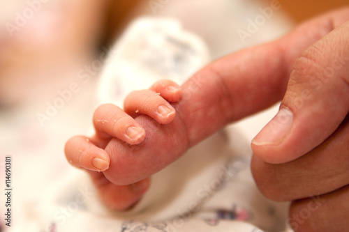 The baby clings to his father's finger