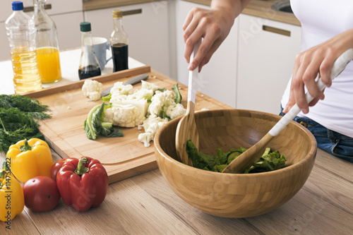 Woman preparing healthy salad in kitchen