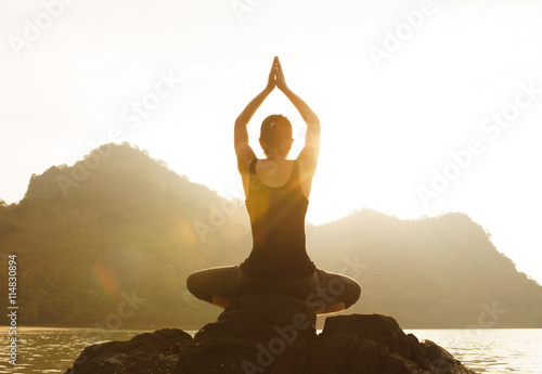 Yoga woman sitting in lotus pose on the beach during sunset (Len