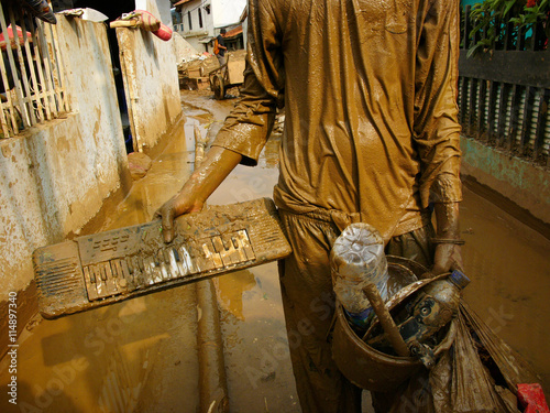 Jakarta, Indonesia - February 12, 2007: A young man displays his flood-soaked keyboard as major El Nino floods and toxic mud devastate the Indonesian capital in Jakarta, Java, Indonesia.