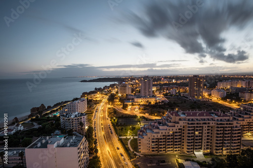 City at the bank of the ocean during sunset.