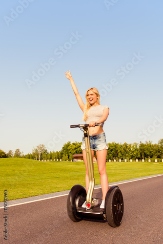Pretty happy girl with raised hand riding a segway