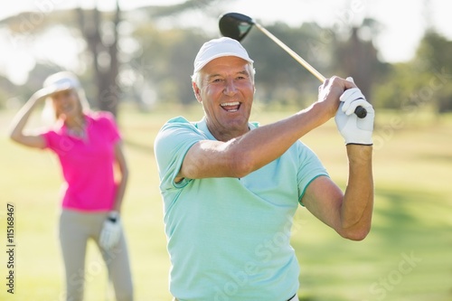 Portrait of cheerful mature golfer holding golf club