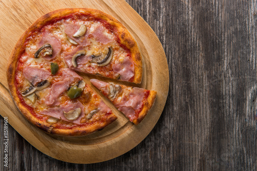 Closeup of Capricciosa Pizza with copy space on wooden table