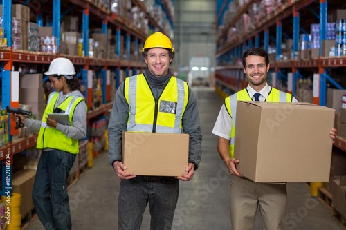 Workers looking at camera while holding box