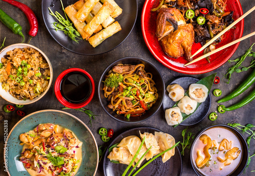 Assorted Chinese food set. Chinese noodles, fried rice, dumplings, peking duck, dim sum, spring rolls. Famous Chinese cuisine dishes on table. Top view. Chinese restaurant concept. Asian style banquet