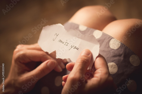 Woman holding a paper note with the text I miss you