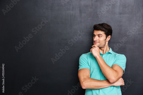 Happy thoughtful young man standing with hands folded