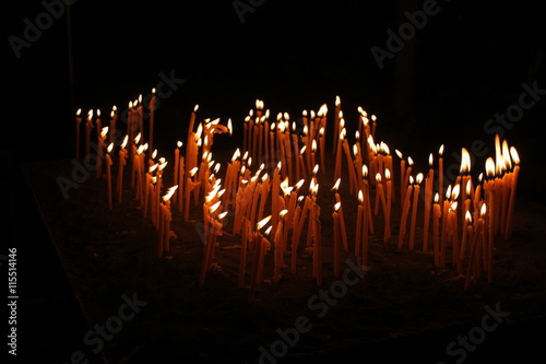 Thin candles lightening in the darkness, spiritual glowing in monastery,