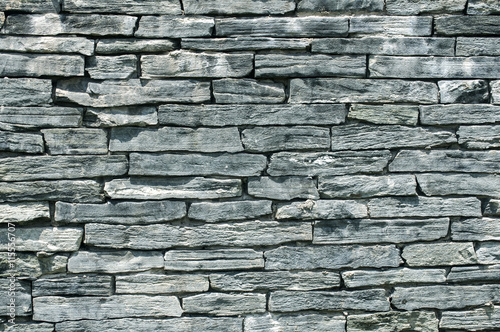 Fence wall made from tiles of gray blue sandstone as background