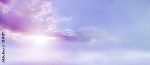 Romantic Lilac Sky scape - beautiful wide lilac and pink clouds lue sky and cloud scape with a burst of sunlight emerging from under the cloud base with plenty of copy space