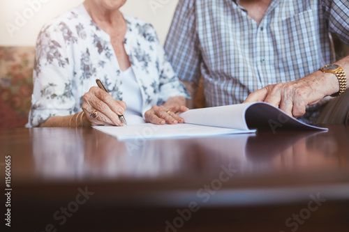 Senior woman signing documents with her husband