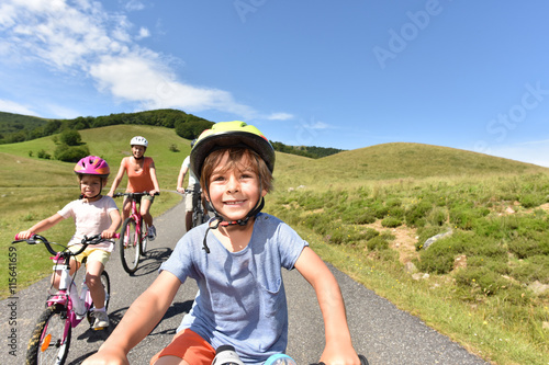 Portrait of little boy riding bike with family