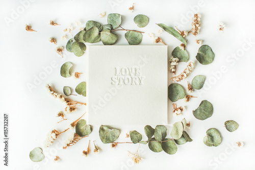 white wedding or family photo album with words "love story", frame with dry and fresh branches isolated on white background. flat lay, overhead view